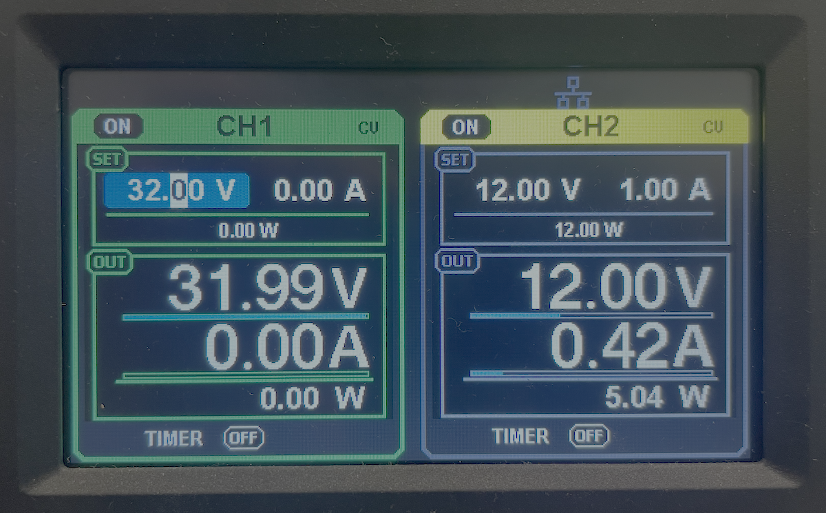 Close-up of a two-channel power supply display: CH1 set to 32.00 V with 31.99 V and 0.00 A output, and CH2 set to 12.00 V with 12.00 V and 0.42 A output, both switched on.